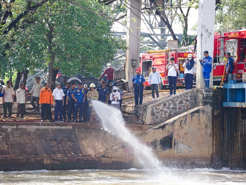 Petugas DLH DKI Jakarta menyemprot busa putih di Pintu Weir 3 Kanal Banjir Timur menggunakan mikroba pengurai pencemar, Rabu (13/8/2025). (Dok-Humas DKI Jakarta)
