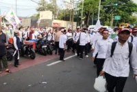 Guru mengenakan ikat kepala putih berjalan kaki menuju Monas saat aksi unjuk rasa di Jakarta Pusat, Kamis 30 Oktober 2025. (TMC PMJ)