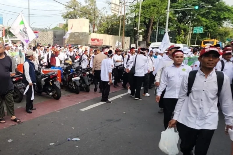 Guru mengenakan ikat kepala putih berjalan kaki menuju Monas saat aksi unjuk rasa di Jakarta Pusat, Kamis 30 Oktober 2025. (TMC PMJ)
