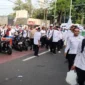 Guru mengenakan ikat kepala putih berjalan kaki menuju Monas saat aksi unjuk rasa di Jakarta Pusat, Kamis 30 Oktober 2025. (TMC PMJ)
