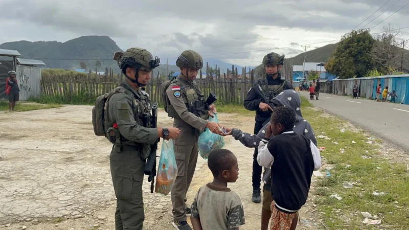 Personel Satgas Operasi Damai Cartenz Paniai membagikan sembako dan makanan ringan kepada warga di Jalan Modern, Enarotali, Papua. Dok: Polri