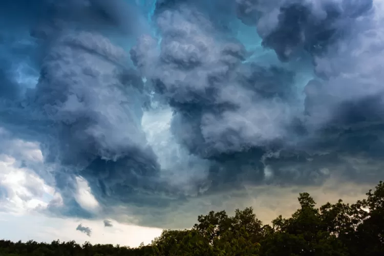 Ilustrasi awan gelap menggantung di langit Jakarta dengan rintik hujan ringan.
(Posnews/Canva)