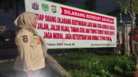 Petugas memasang spanduk larangan asusila di Taman Daan Mogot.