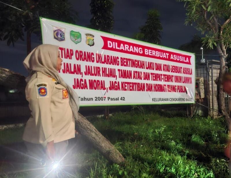 Petugas memasang spanduk larangan asusila di Taman Daan Mogot.