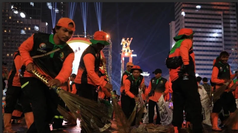 Petugas Pasukan Oranye DLH DKI Jakarta membersihkan sampah sisa perayaan Malam Tahun Baru 2026 di kawasan Bundaran HI, Jakarta. (Posnews/Dinas LH DKI)