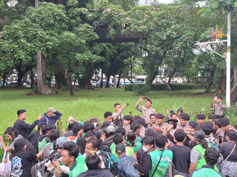 Polisi bagikan air mineral dan snack saat mengawal aksi demo ojek online di sekitar Kedutaan Besar Amerika Serikat, Jakarta. (Posnews/Ist)