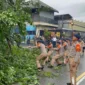 Personel Brimob Polda Metro Jaya mengevakuasi pohon tumbang di Jalan RE Martadinata Ciputat saat hujan dan badai petir. (Posnews/Ist)