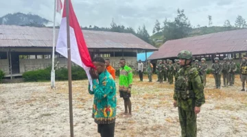 Tiga mantan anggota OPM mencium bendera Merah Putih saat ikrar setia NKRI di Distrik Sinak Papua Tengah. (Posnews/ist)
