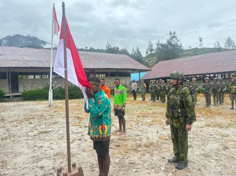 Tiga mantan anggota OPM mencium bendera Merah Putih saat ikrar setia NKRI di Distrik Sinak Papua Tengah. (Posnews/ist)