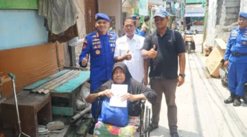 Direktur Polairud Polda Metro Jaya, Kombes Pol Mustofa menyerahkan kursi roda kepada warga pesisir Muara Angke yang menderita stroke. (Posnews/ist)