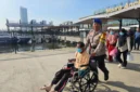 Polisi membantu penumpang kursi roda di Dermaga Kali Adem Muara Angke. (Posnews/Ist)