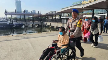 Polisi membantu penumpang kursi roda di Dermaga Kali Adem Muara Angke. (Posnews/Ist)