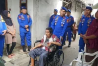 Direktur Polairud Polda Metro Jaya Kombes Pol Mustofa menyerahkan kursi roda kepada warga lumpuh di kawasan pesisir Cilincing Jakarta Utara. (Posnews/Ist)