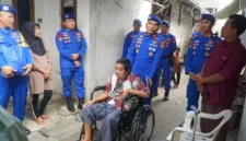 Direktur Polairud Polda Metro Jaya Kombes Pol Mustofa menyerahkan kursi roda kepada warga lumpuh di kawasan pesisir Cilincing Jakarta Utara. (Posnews/Ist)