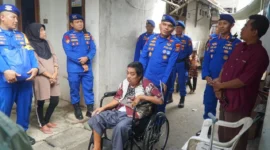 Direktur Polairud Polda Metro Jaya Kombes Pol Mustofa menyerahkan kursi roda kepada warga lumpuh di kawasan pesisir Cilincing Jakarta Utara. (Posnews/Ist)