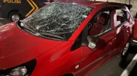Mobil Honda Brio merah mengalami kerusakan parah setelah diamuk massa di kawasan Grand Galaxy Park, Bekasi Selatan, diduga terkait insiden tabrak lari. (Posnews/Ist)