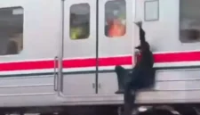 Petugas KAI Commuter mengamankan pria yang bergelantungan di sisi luar rangkaian Commuter Line di Stasiun Ancol. (Posnews/Ist)