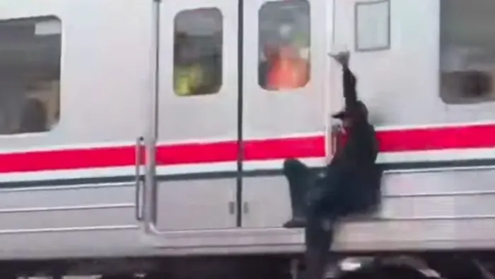 Petugas KAI Commuter mengamankan pria yang bergelantungan di sisi luar rangkaian Commuter Line di Stasiun Ancol. (Posnews/Ist)