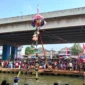 Ribuan warga menyaksikan lomba panjat pinang di atas Sungai Kalimalang, Cipinang Melayu, Jakarta Timur. (Posnews/MR)