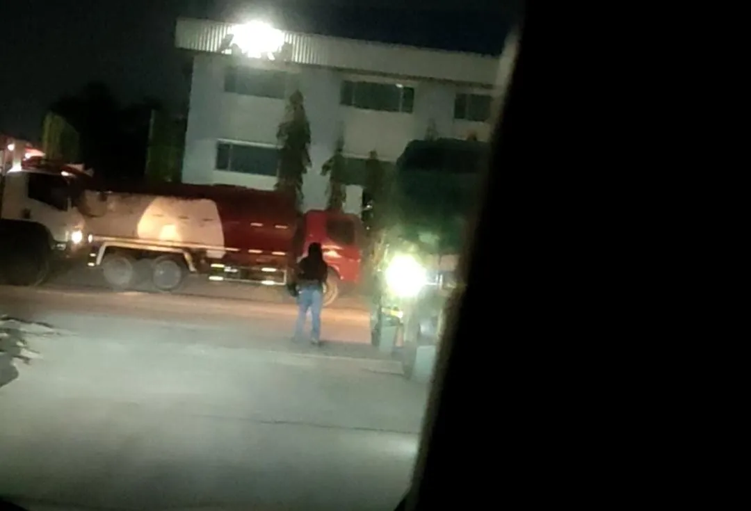 Penjual kopi keliling menghampiri kendaraan kontainer yang terparkir di kawasan KBN Marunda pada malam hari. (Posnews/MR)
