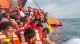 Petugas mengevakuasi penumpang KMP Batumandi yang terbakar di perairan dekat Pelabuhan Merak, Cilegon, Banten.
