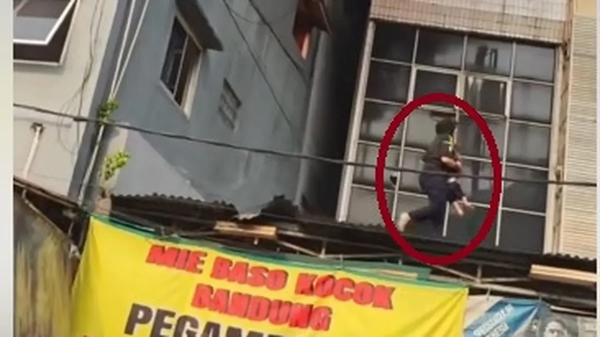 Wanita berhijab menyelamatkan anak saat kebakaran rumah makan Padang di Rawamangun, Jakarta Timur, Jumat 9 Oktober 2026.
