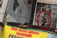 Wanita berhijab menyelamatkan anak saat kebakaran rumah makan Padang di Rawamangun, Jakarta Timur, Jumat 9 Oktober 2026.
