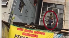 Wanita berhijab menyelamatkan anak saat kebakaran rumah makan Padang di Rawamangun, Jakarta Timur, Jumat 9 Oktober 2026.
